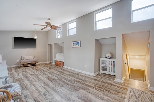 unfurnished living room with a high ceiling, baseboards, and wood finished floors