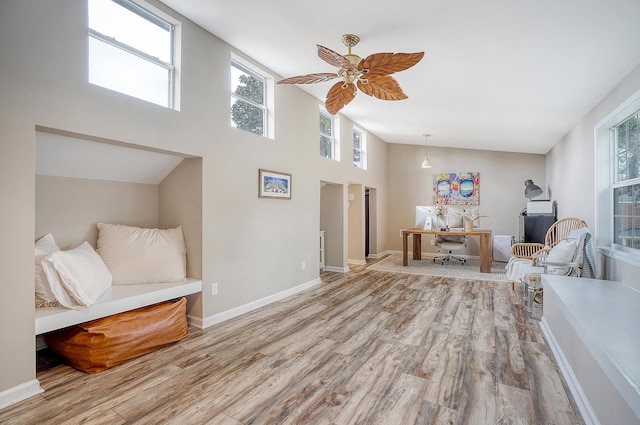 interior space featuring ceiling fan, a high ceiling, wood finished floors, and baseboards