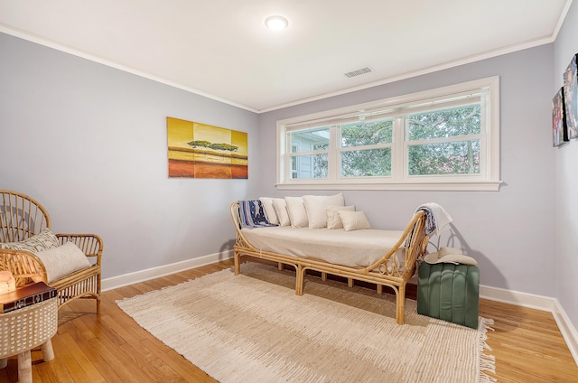 living area featuring light wood finished floors, ornamental molding, visible vents, and baseboards