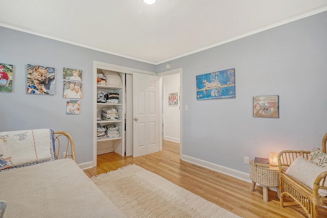 bedroom featuring light wood-style floors, a closet, crown molding, and baseboards