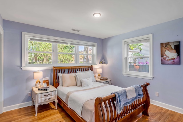 bedroom with baseboards, visible vents, and wood finished floors