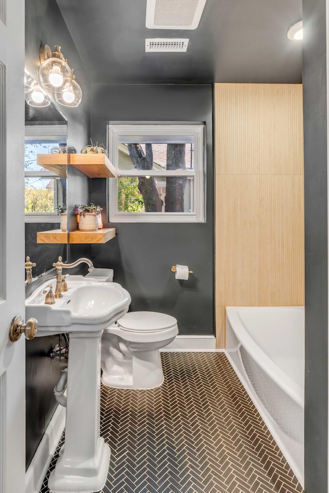 bathroom featuring a tub, baseboards, visible vents, and toilet