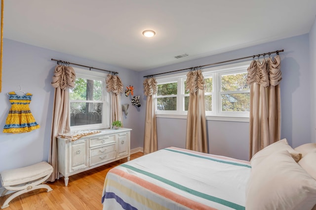 bedroom with light wood finished floors and visible vents