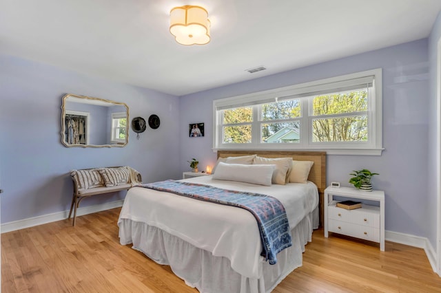 bedroom featuring light wood-style floors, visible vents, multiple windows, and baseboards