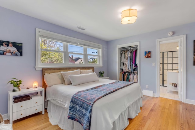 bedroom with light wood finished floors, baseboards, visible vents, and a closet