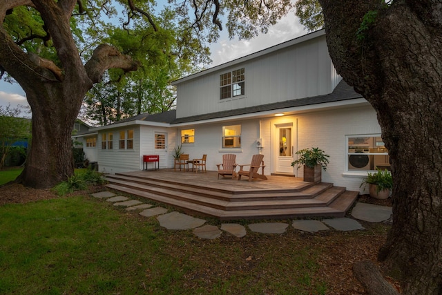 rear view of house featuring brick siding and a wooden deck