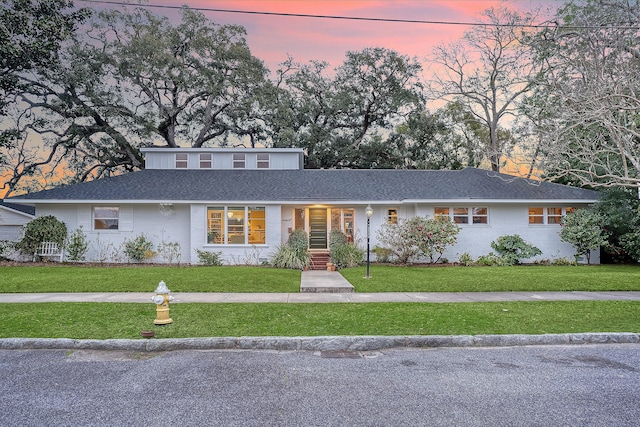 view of front of house with a front lawn, roof with shingles, and brick siding