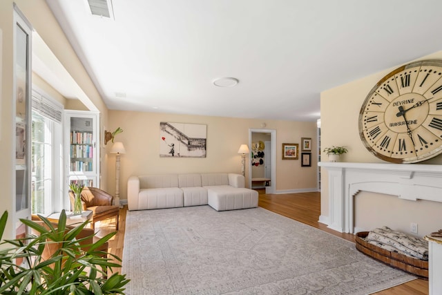 living area with baseboards, visible vents, and wood finished floors