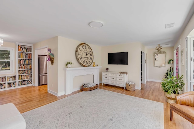 living room featuring wood finished floors, visible vents, and baseboards