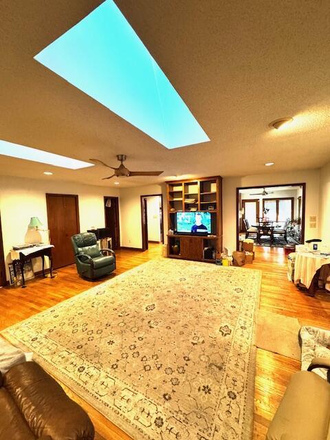 living room with a textured ceiling, hardwood / wood-style flooring, and ceiling fan