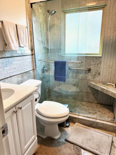 bathroom with a shower with door, vanity, and toilet