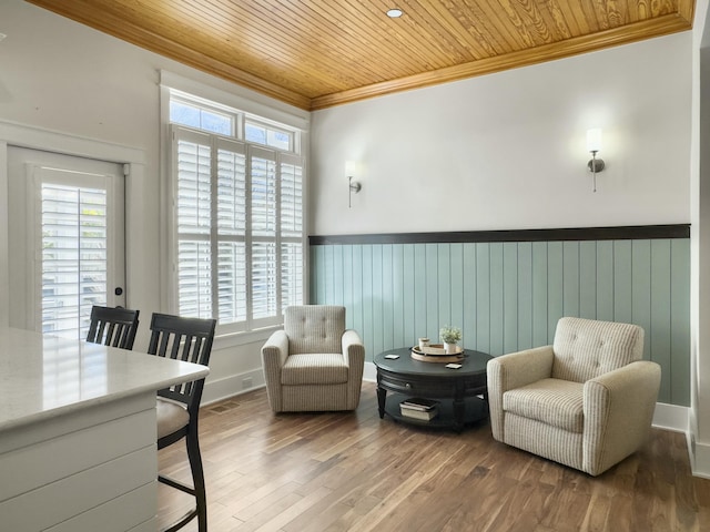 sitting room with wood finished floors, wood ceiling, wainscoting, and ornamental molding