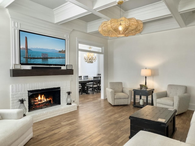 living room featuring a notable chandelier, a brick fireplace, coffered ceiling, and wood finished floors