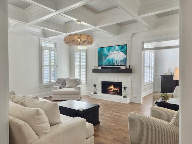 living area featuring wood finished floors, a brick fireplace, a healthy amount of sunlight, and beam ceiling