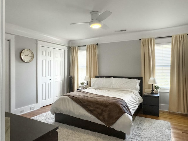 bedroom featuring a closet, visible vents, multiple windows, and wood finished floors