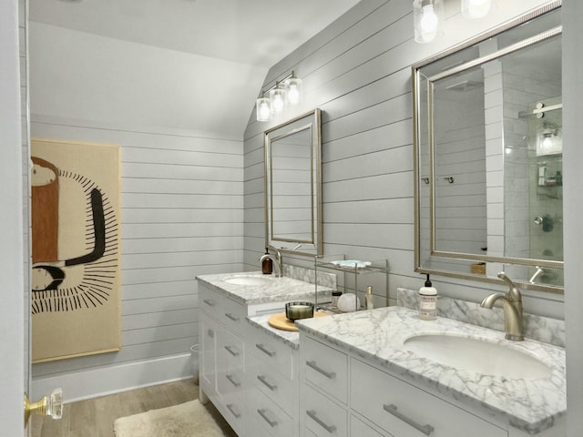 full bathroom with double vanity, wood walls, and a sink