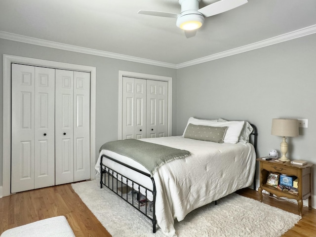 bedroom with ornamental molding, a ceiling fan, multiple closets, and wood finished floors