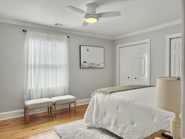 bedroom featuring baseboards, visible vents, light wood-style flooring, ceiling fan, and crown molding