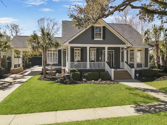 bungalow featuring driveway, a porch, a shingled roof, a carport, and a front lawn