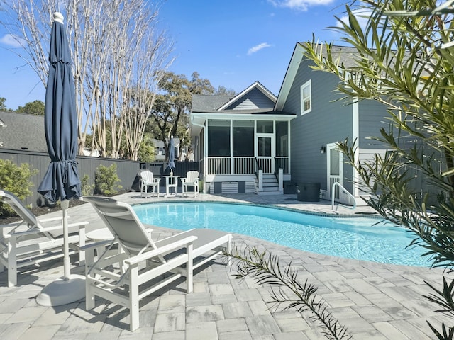 view of pool with a patio, fence, a fenced in pool, a sunroom, and entry steps