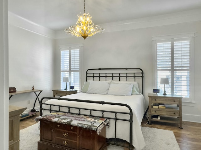 bedroom featuring baseboards, an inviting chandelier, and wood finished floors