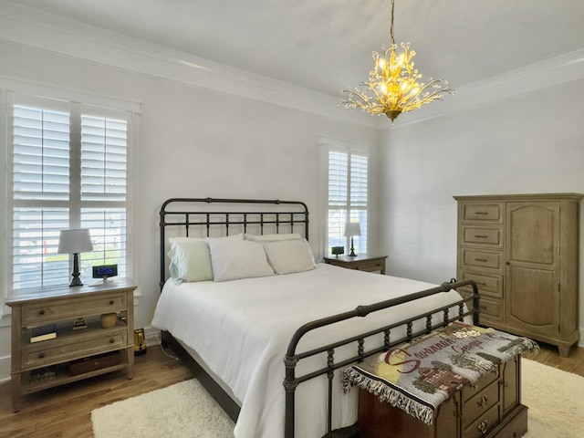 bedroom featuring wood finished floors, a chandelier, and ornamental molding