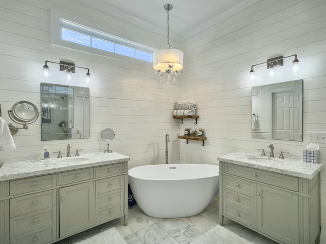 bathroom with a sink, two vanities, an inviting chandelier, and a freestanding bath