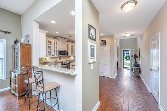 511 Nandina Dr, Goose Creek, SC 29445 - interior space with glass insert cabinets, a breakfast bar, stainless steel appliances, light stone counters, and dark wood-style floors