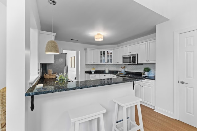 1441 Waterside Ct, Mount Pleasant, SC 29464 - kitchen featuring appliances with stainless steel finishes, a peninsula, glass insert cabinets, light wood-style flooring, and tasteful backsplash