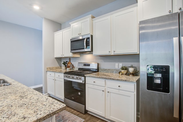 kitchen featuring light stone countertops, stainless steel appliances, dark wood-type flooring, and white cabinetry