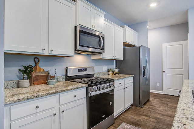 kitchen with light stone counters, white cabinets, stainless steel appliances, and dark wood-type flooring