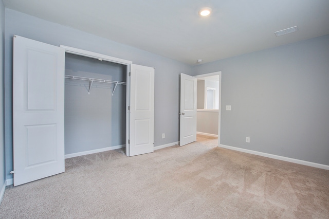 unfurnished bedroom featuring light colored carpet and a closet