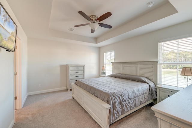 carpeted bedroom featuring a raised ceiling and ceiling fan