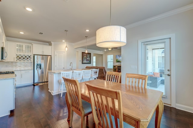 dining area featuring dark wood-type flooring and crown molding