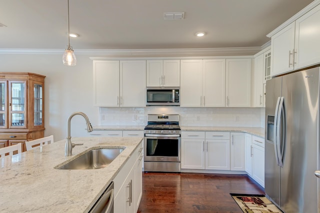 kitchen with hanging light fixtures, appliances with stainless steel finishes, sink, and white cabinets