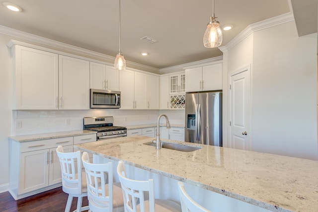 kitchen with appliances with stainless steel finishes, pendant lighting, sink, white cabinets, and crown molding