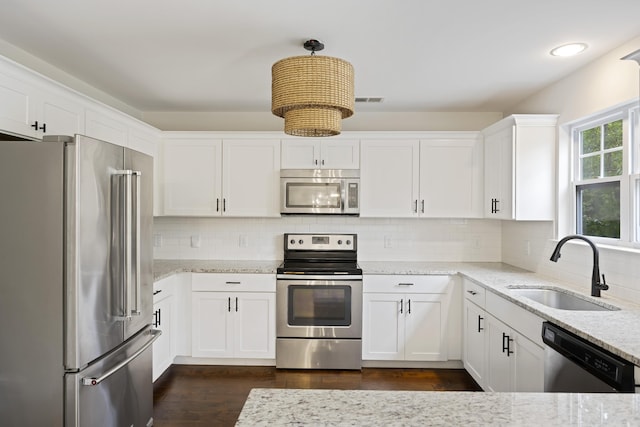 1506 Southwick Dr, Johns Island, SC 29455 - kitchen featuring appliances with stainless steel finishes, a sink, light stone countertops, white cabinetry, and backsplash