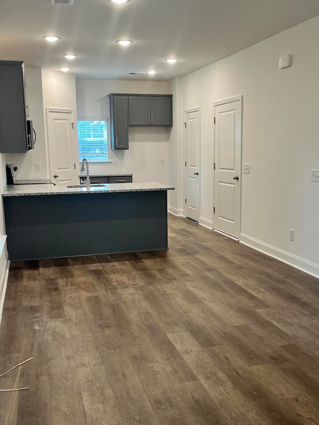 kitchen with gray cabinets, dark hardwood / wood-style flooring, range, sink, and light stone counters