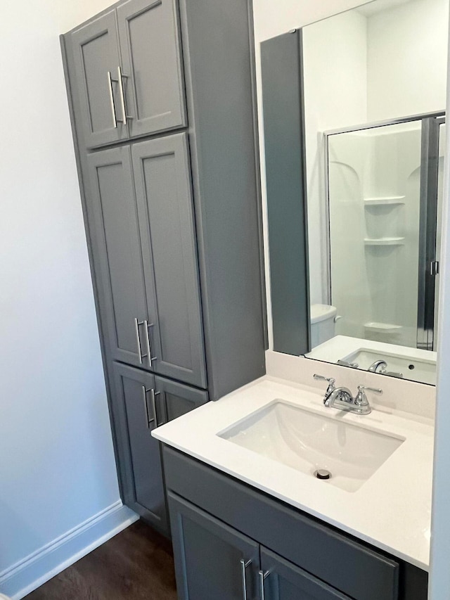 bathroom featuring wood-type flooring, a shower with door, vanity, and toilet