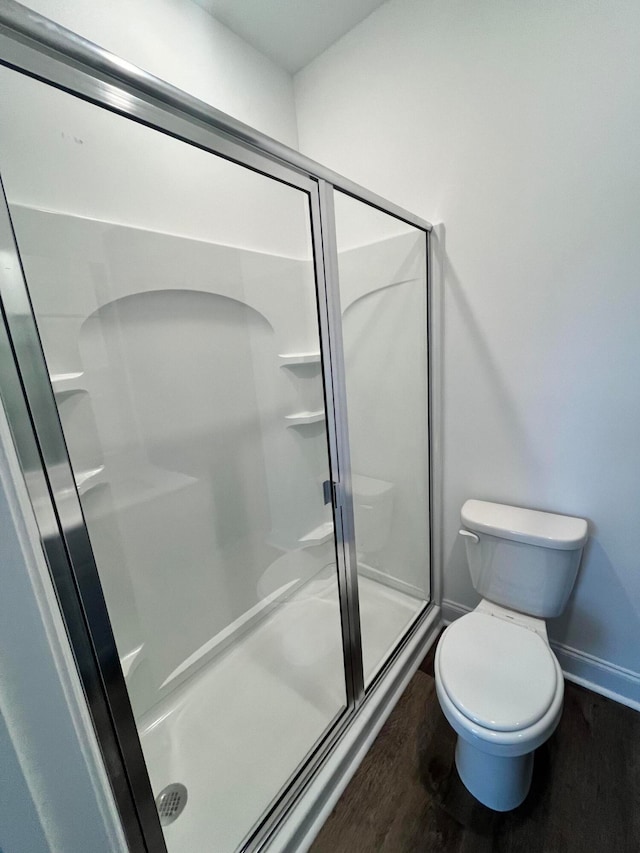 bathroom featuring walk in shower, toilet, and wood-type flooring