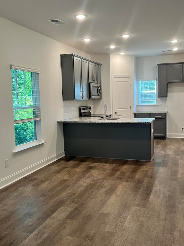 kitchen featuring gray cabinetry, light stone counters, sink, dark hardwood / wood-style floors, and appliances with stainless steel finishes