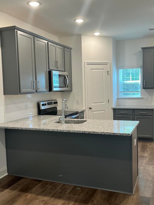 kitchen with light stone countertops, dark hardwood / wood-style floors, sink, and gray cabinetry