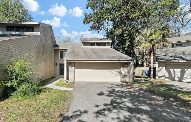 mid-century modern home with driveway and fence