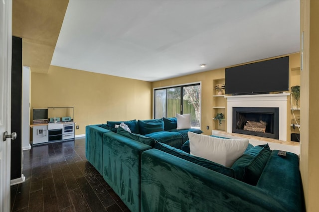 living area with a fireplace with raised hearth, baseboards, and wood finished floors