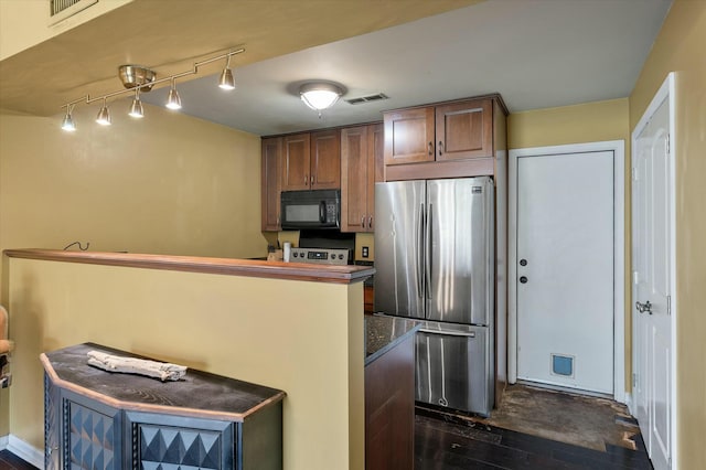 kitchen with visible vents, dark countertops, black microwave, and freestanding refrigerator