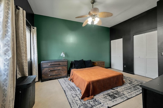 bedroom with carpet floors, ceiling fan, and multiple closets