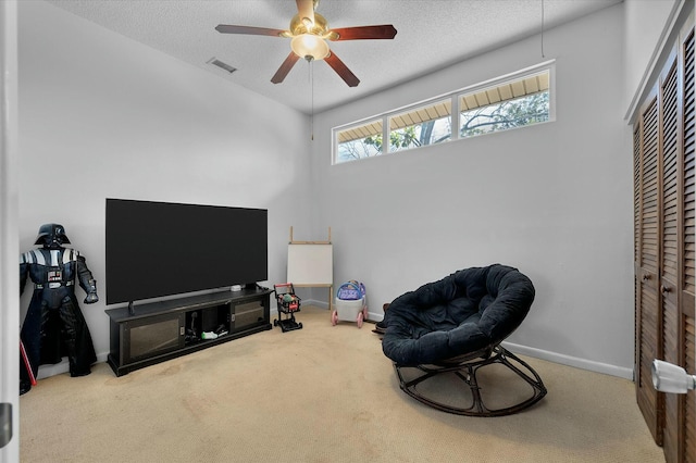 sitting room featuring baseboards, visible vents, carpet floors, ceiling fan, and a textured ceiling