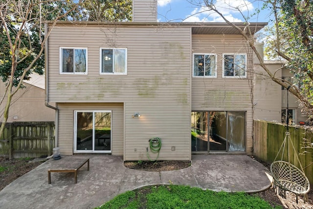 back of property with a patio area, a chimney, and fence