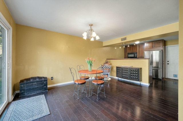 dining room with a notable chandelier, wood finished floors, visible vents, and baseboards