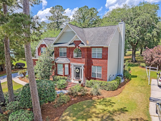 colonial inspired home featuring a front lawn, brick siding, a chimney, and central AC
